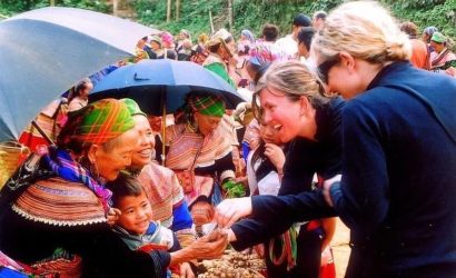 Des touristes étrangères échangeant de manière amicale avec des femmes H'Mong au marché de Bắc Hà.