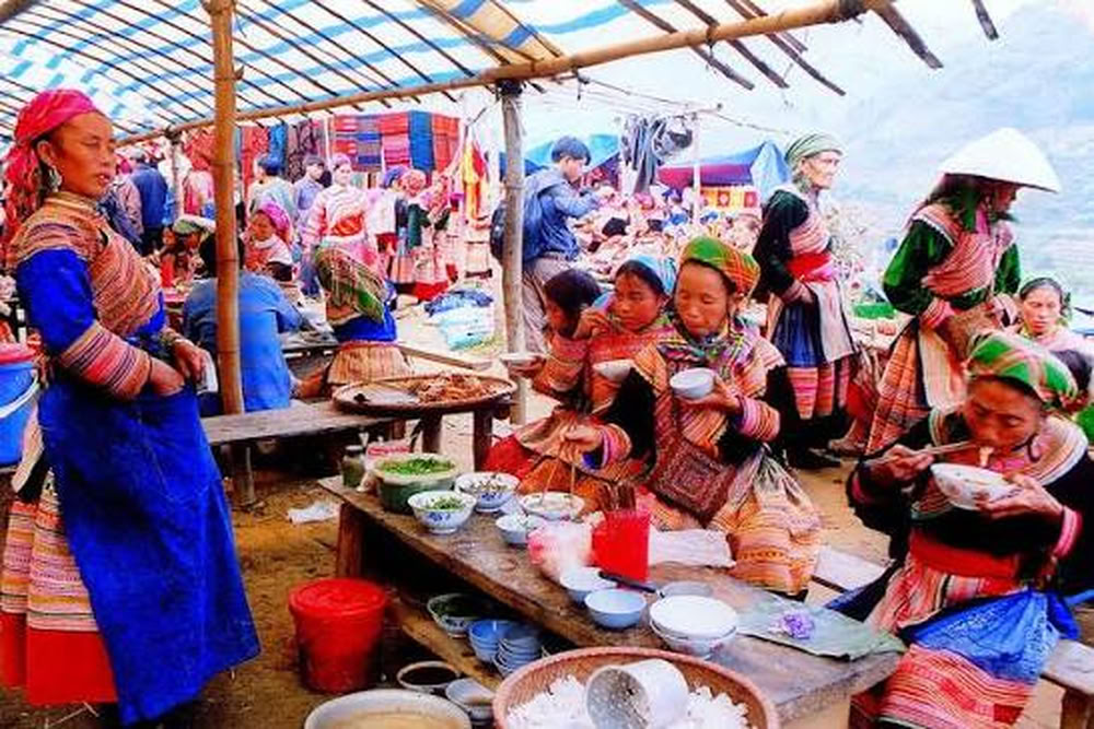 Femmes H'Mong Fleur savourant des plats traditionnels aux échoppes du marché de Cán Cấu.