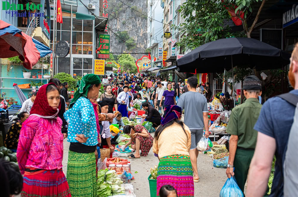 Allée commerçante animée où locaux et touristes se croisent au marché traditionnel de Đồng Văn.