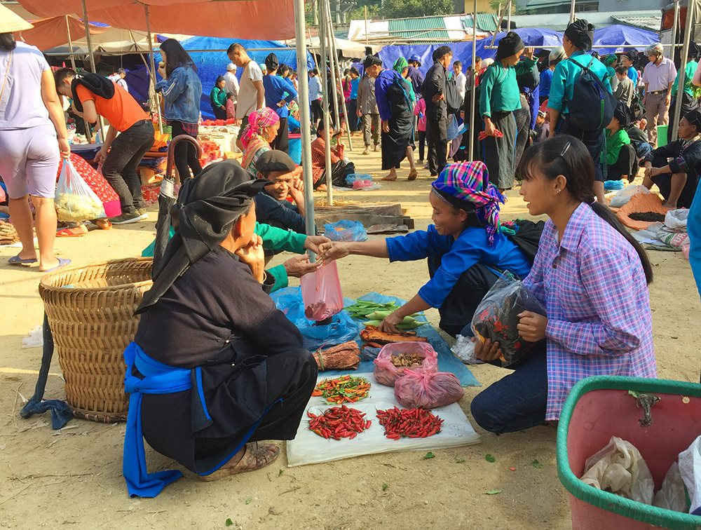 Scène animée au marché hebdomadaire de Hoang Su Phi où des femmes en costumes traditionnels échangent des produits locaux.