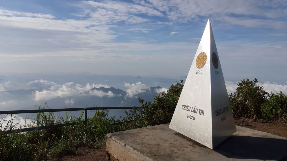 Le sommet du mont Chiêu Lầu Thi à 2402 mètres d'altitude surplombant une mer de nuages sous un ciel dégagé.